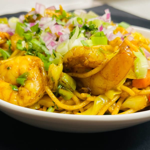 Close-up of Indian Express Denver's shrimp noodles with vegetables, red onions, and green onions.