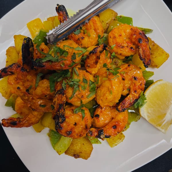 Indian Express Denver's grilled shrimp with bell peppers, pineapple, and cilantro, served with a lemon wedge.
