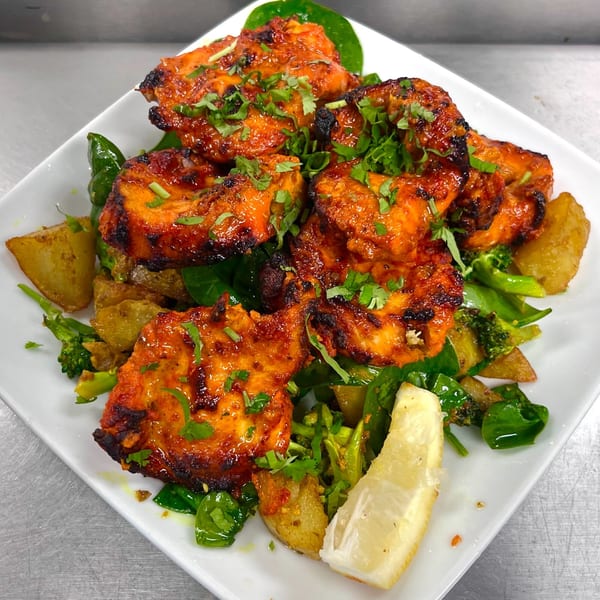 Indian Express Denver's chicken tikka, garnished with cilantro, served with potatoes, broccoli, and lemon.