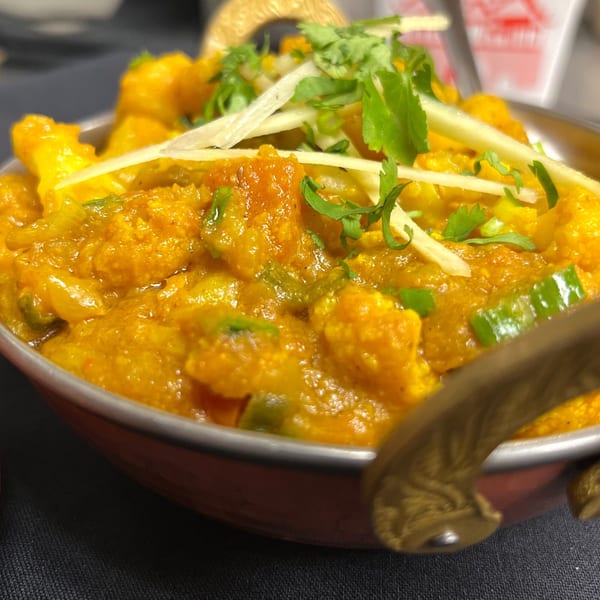 Close-up of Indian Express Denver's Gobi Manchurian, a vibrant orange cauliflower dish garnished with cilantro and ginger.