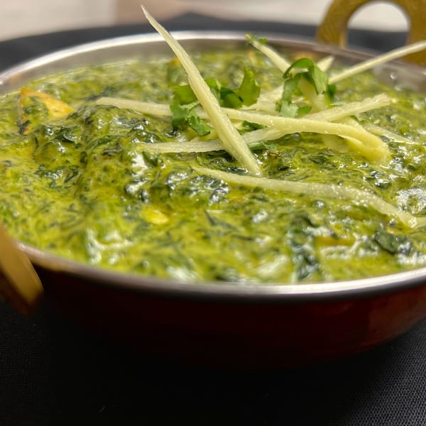 Palak Paneer, a vibrant green Indian spinach and cheese dish, garnished with ginger and cilantro.