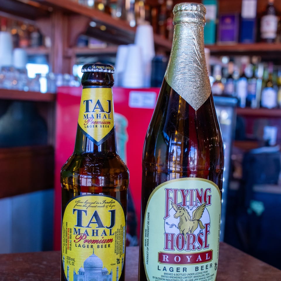 Two Indian beers, Taj Mahal Premium and Flying Horse Royal Lager, on a bar counter.