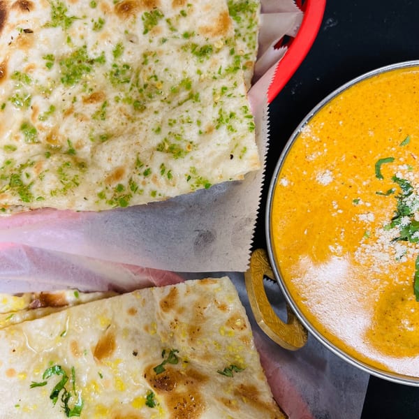 Indian Express Denver's naan bread with herbs and a bowl of creamy orange curry.