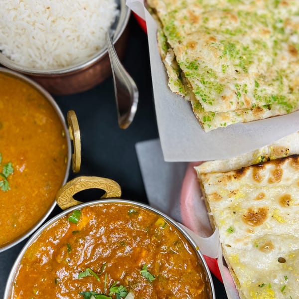 Overhead view of Indian Express Denver's Indian dishes: rice, two curries, and two types of naan bread.