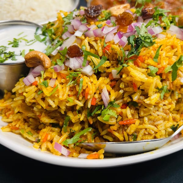 Close-up of India Express's chicken biryani, garnished with cashews, raisins, red onions, and cilantro.