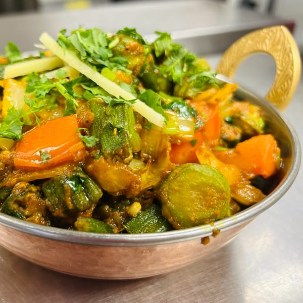 Indian Express Denver's Bhindi Masala, a vibrant okra and vegetable curry, garnished with fresh cilantro and ginger.
