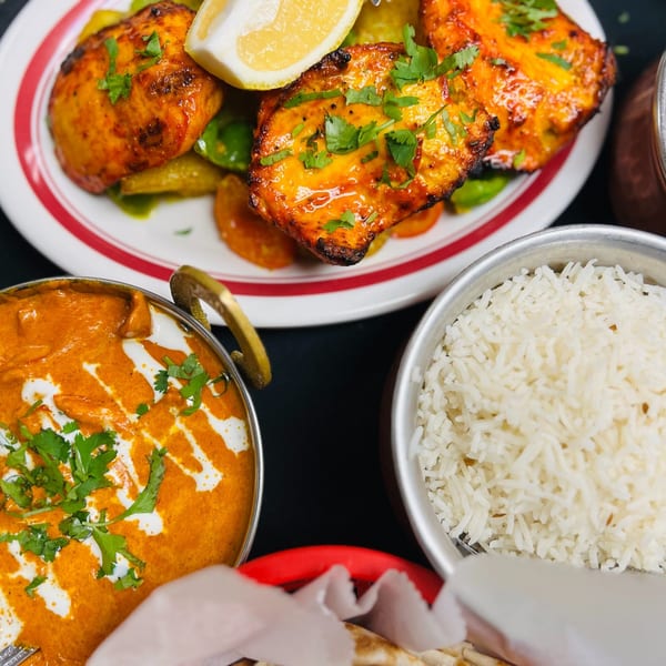 Indian Express Denver's butter chicken, tandoori chicken, and rice, with naan bread in a basket.