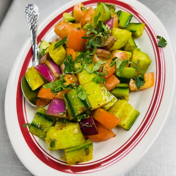 Close-up of an Indian kachumber salad with cucumber, tomato, and onion, garnished with cilantro.