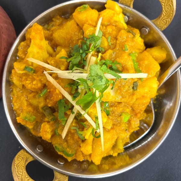 Aloo Gobi from India Express Denver, a vibrant Indian potato and cauliflower curry in a metal bowl.