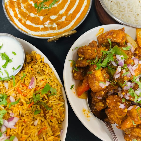 Indian Express Denver's butter chicken, chili chicken, biryani, and rice, garnished with cilantro and onions.