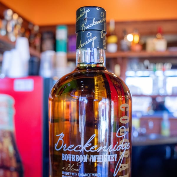 A bottle of Breckenridge Bourbon Whiskey with a blurred bar background.
