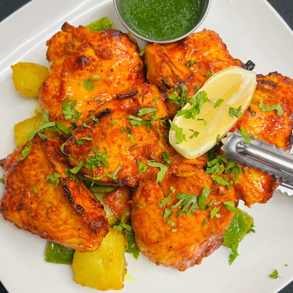 Tandoori chicken from India Express Denver, garnished with cilantro, lemon, and green chutney.