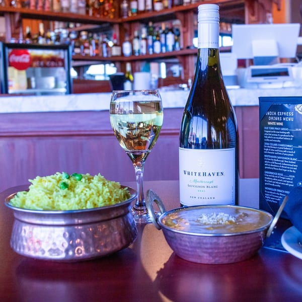 Indian Express Denver: yellow rice, curry, a glass of white wine, and a bottle of Whitehaven Sauvignon Blanc.