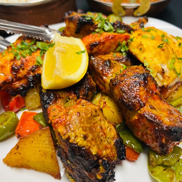 Close-up of Indian Express Denver's grilled chicken tikka with bell peppers, potatoes, and lemon.