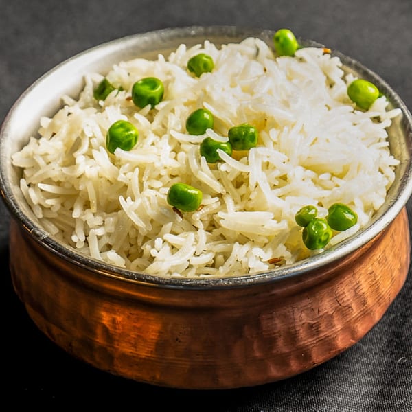Peas Pulao, fluffy white basmati rice with green peas, served in a hammered copper bowl.