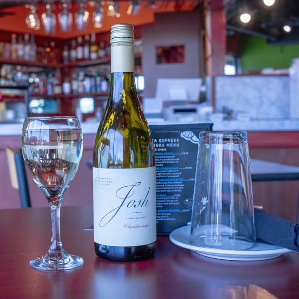 A bottle of Josh Cellars Chardonnay and a wine glass on a table at India Express Denver.