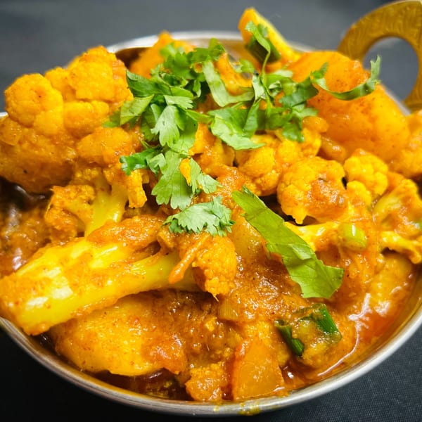 Close-up of Aloo Gobi, a vibrant Indian dish with cauliflower and potatoes, garnished with cilantro.