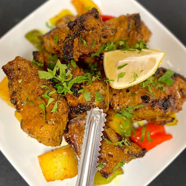 Close-up of Indian Express Denver's chicken tikka with bell peppers, potatoes, cilantro, and lemon.
