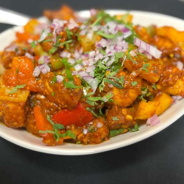 Close-up of Indian Express Denver's spicy chicken dish, garnished with red onions and cilantro.