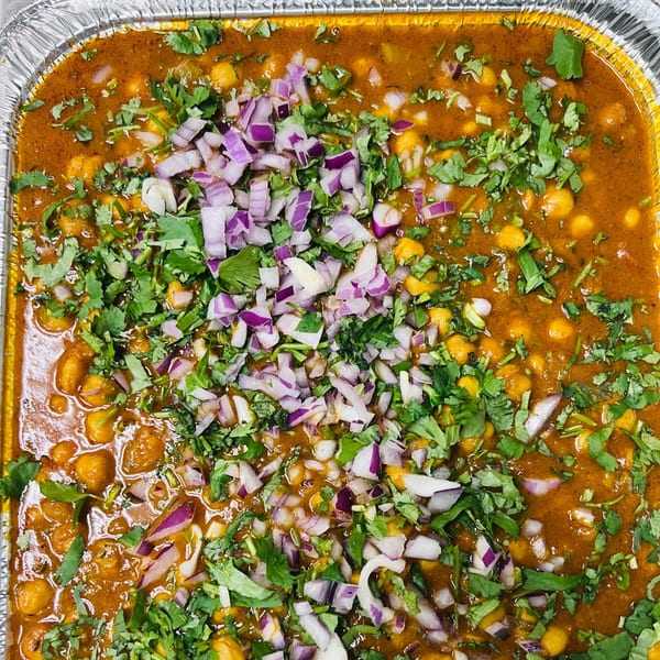 Close-up of Indian chana masala, a chickpea curry, topped with fresh cilantro and diced red onions.