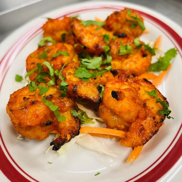 Close-up of Indian Express Denver's vibrant orange chicken tikka, garnished with fresh cilantro on a white plate.