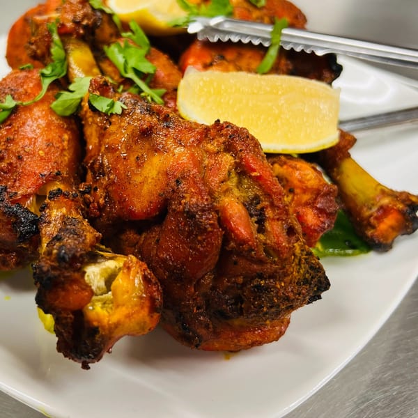 Platter of India Express Denver's Tandoori Chicken, garnished with cilantro and lemon wedges.