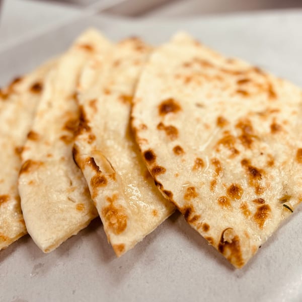 Close-up of four pieces of golden-brown naan bread, lightly charred, from India Express Denver.